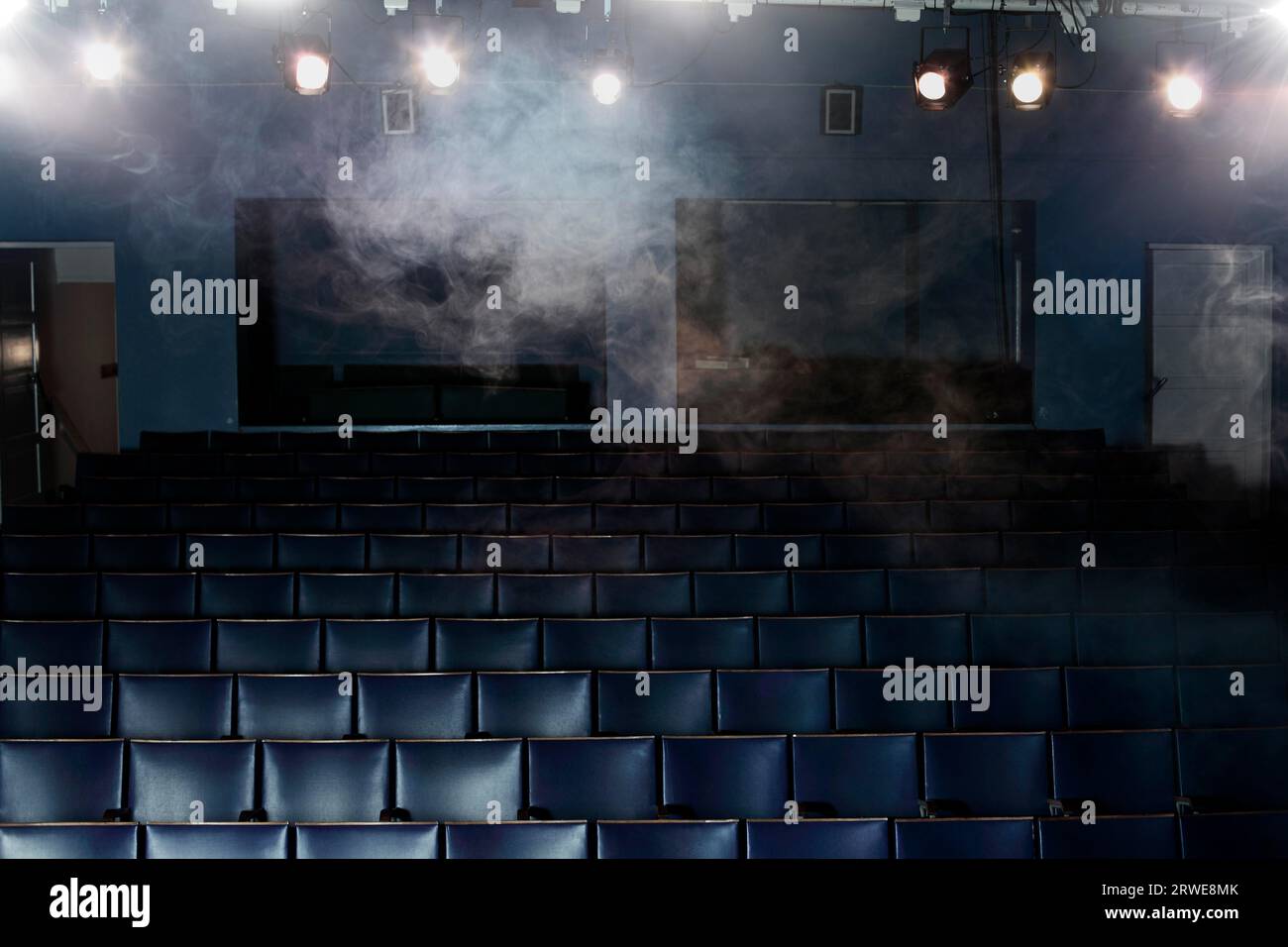 Leere Sitze eines kleinen alten Theaters aus der Sicht der Bühne. Einige Rauch- und Lichteffekte Stockfoto