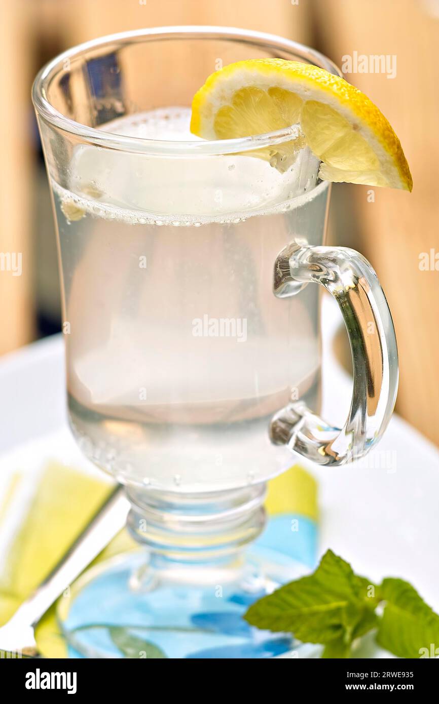 Limonade mit Zitronenscheibe vor dunklem Hintergrund Stockfoto