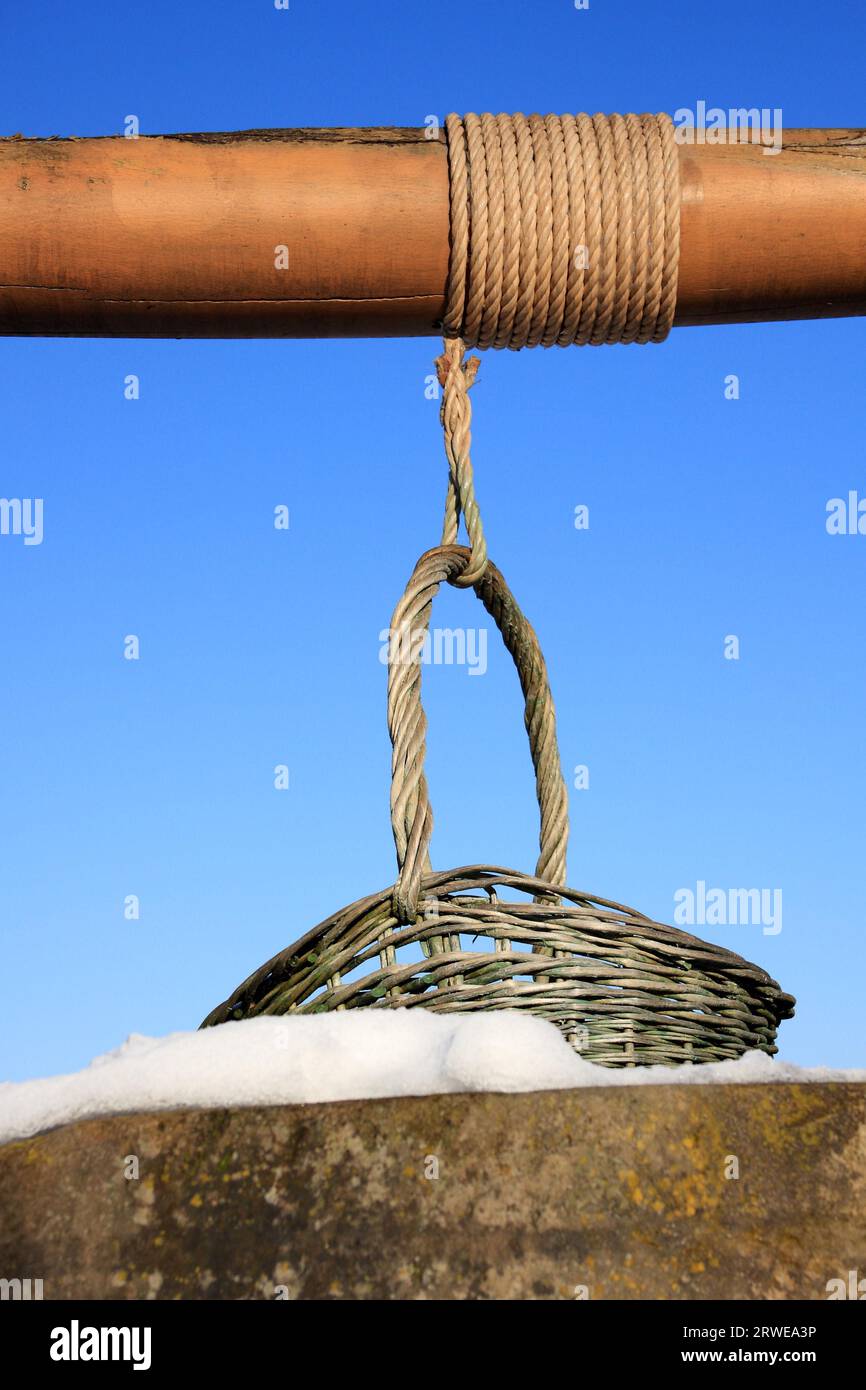 Korb mit einer Seilwinde vor einem gefrorenen Brunnen in Lothringen, Hintergrund blauer Himmel Stockfoto