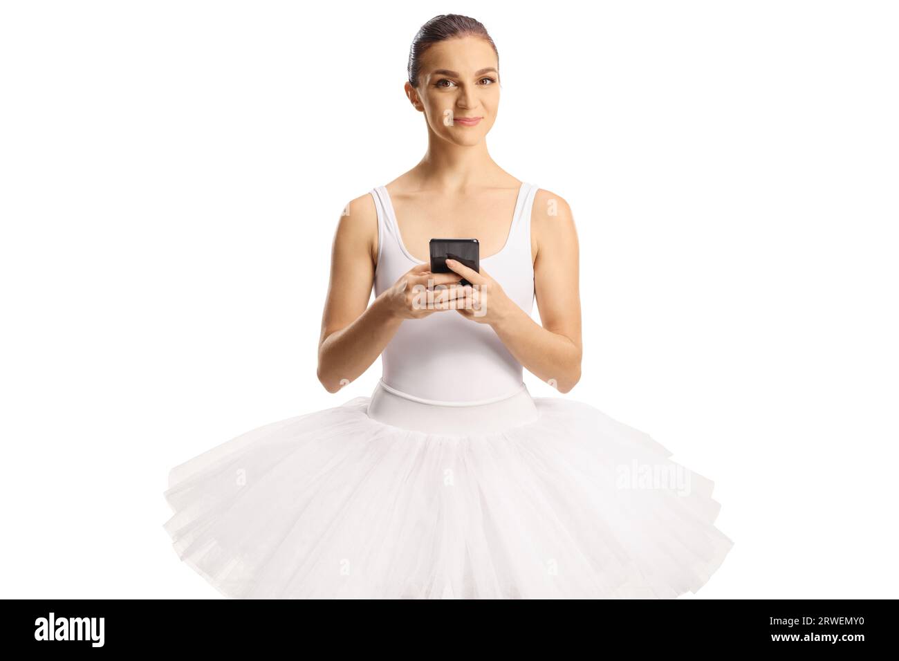 Ballerina in einem weißen Kleid, die ein Smartphone hält und die Kamera isoliert auf weißem Hintergrund betrachtet Stockfoto