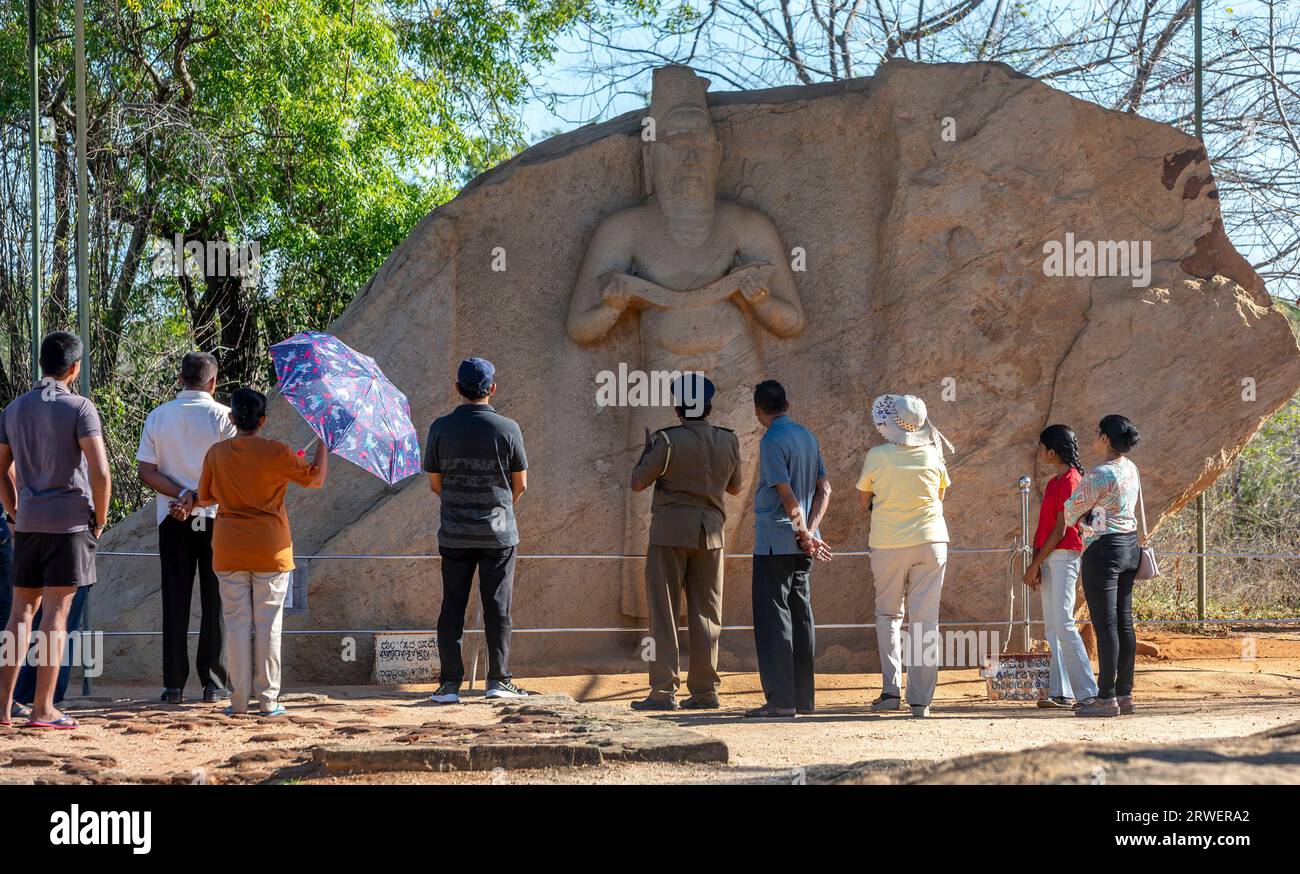Besucher bewundern eine aus Stein geschnitzte Skulptur von König Parakramabahu dem Großen in Potgul Vihara in der antiken Stadt Polonnaruwa in Sri Lanka. Stockfoto