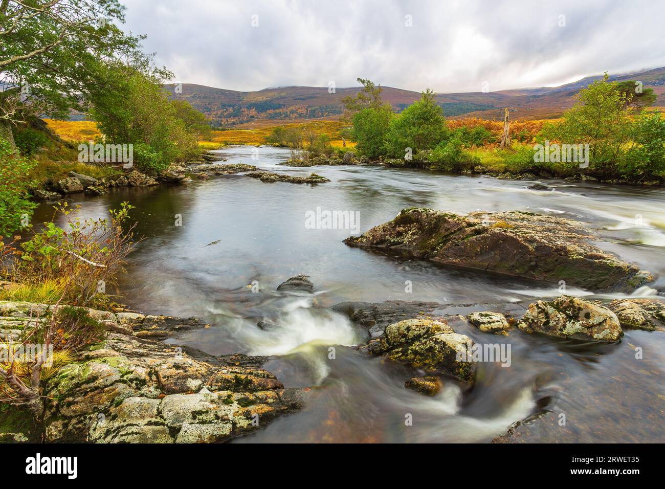 Der Fluss Farrar fließt schnell über moosbedeckte Felsen in Glen Strathfarrar, Highlands of Scotland. Eine herbstliche Szene mit goldenen Bracken, Bergen Stockfoto