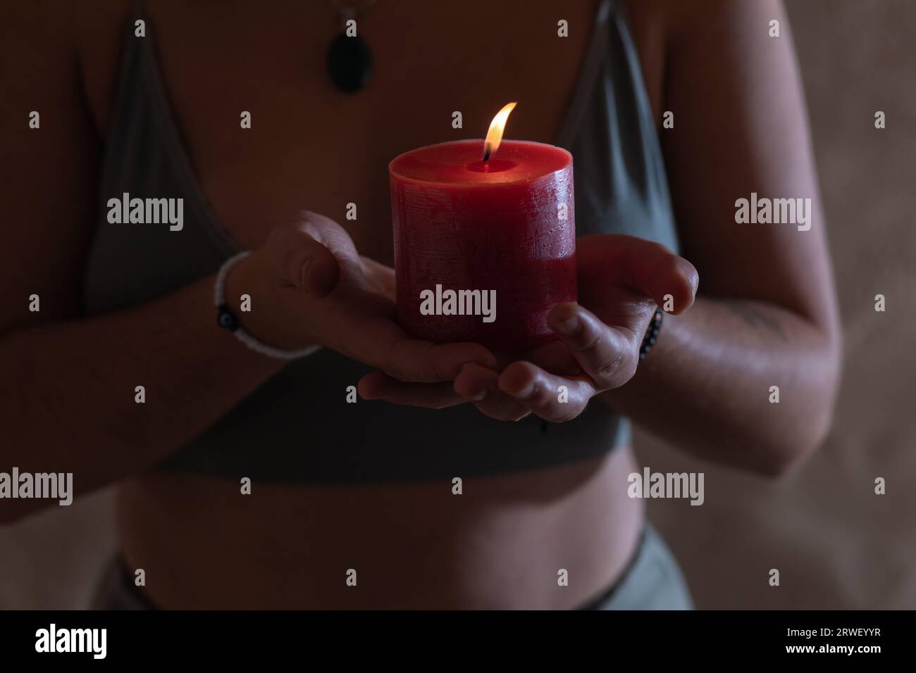 Nahporträt der Hände einer jungen Frau, die eine rote Kerze hält Stockfoto