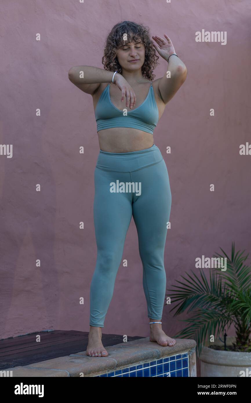 Eine junge Frau steht in einer Yoga-Pose und bewegt ihre Arme in einem anmutigen, meditativen Tanz Stockfoto