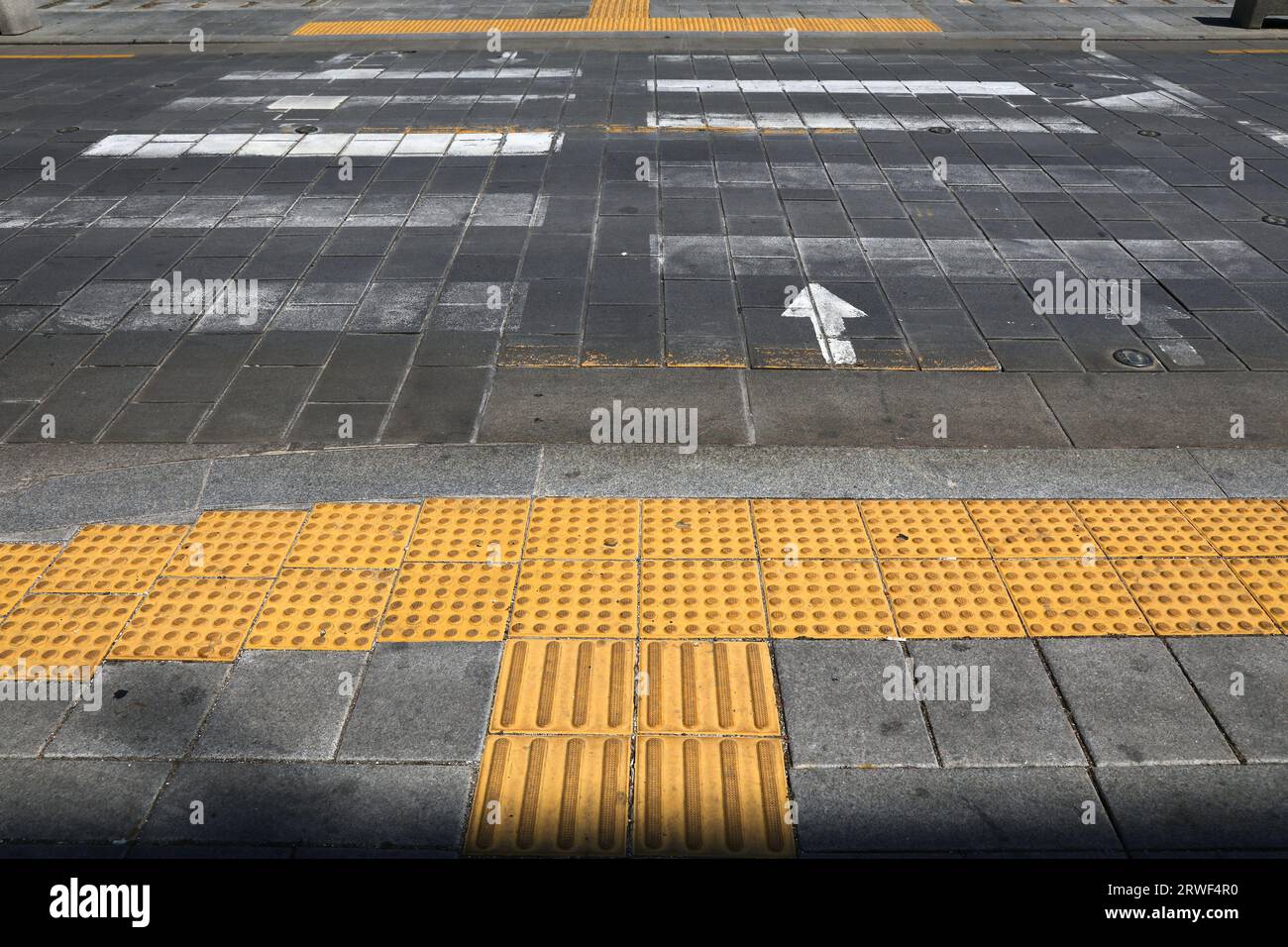 Taktiles Pflaster (Tendschi-Blöcke) am Fußgängerübergang in Seoul, Südkorea. Infrastruktur für Sehbehinderte. Stockfoto