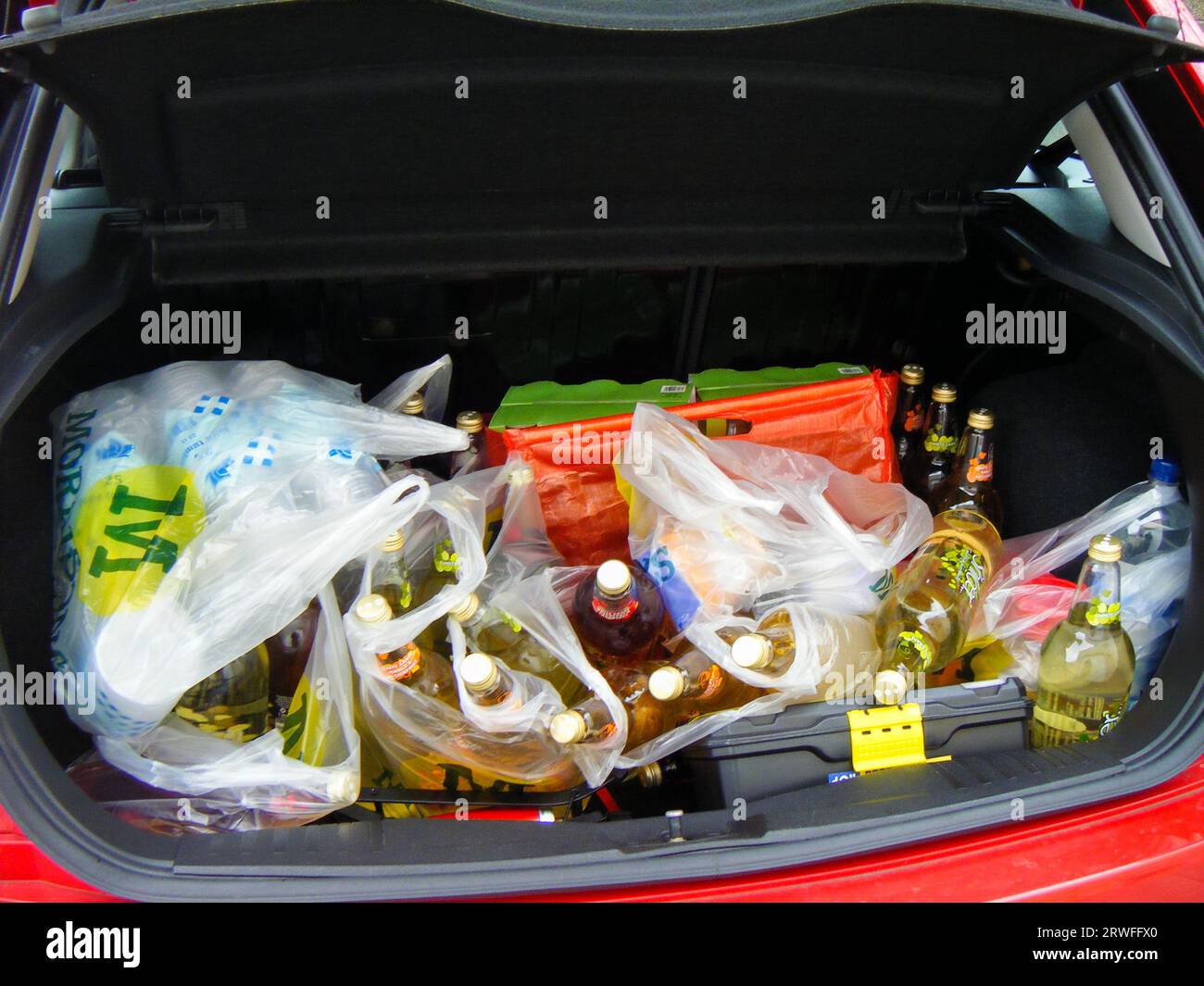 Autostiefel voll mit alkoholfreien Glasflaschen. Verschiedene Geschmacksrichtungen von Shloer Sparkling Juice Drinks. Morrisons Kunststofftragetaschen Stockfoto
