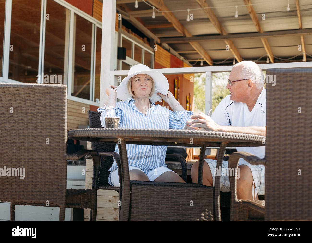 Glückliches reifes Paar mittleren Alters, das redet, Frau zeigt ihren Hut, flirtet. Auf ein Date in einem Café. Stockfoto