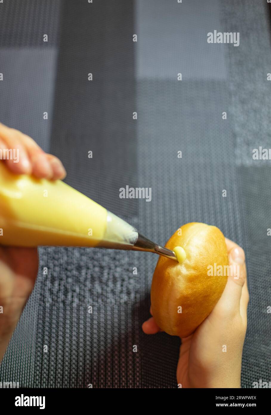 Hände, die Krapfen mit Vanillecreme füllen. Nachtisch aus Deutschland wie Donuts-Teig Stockfoto