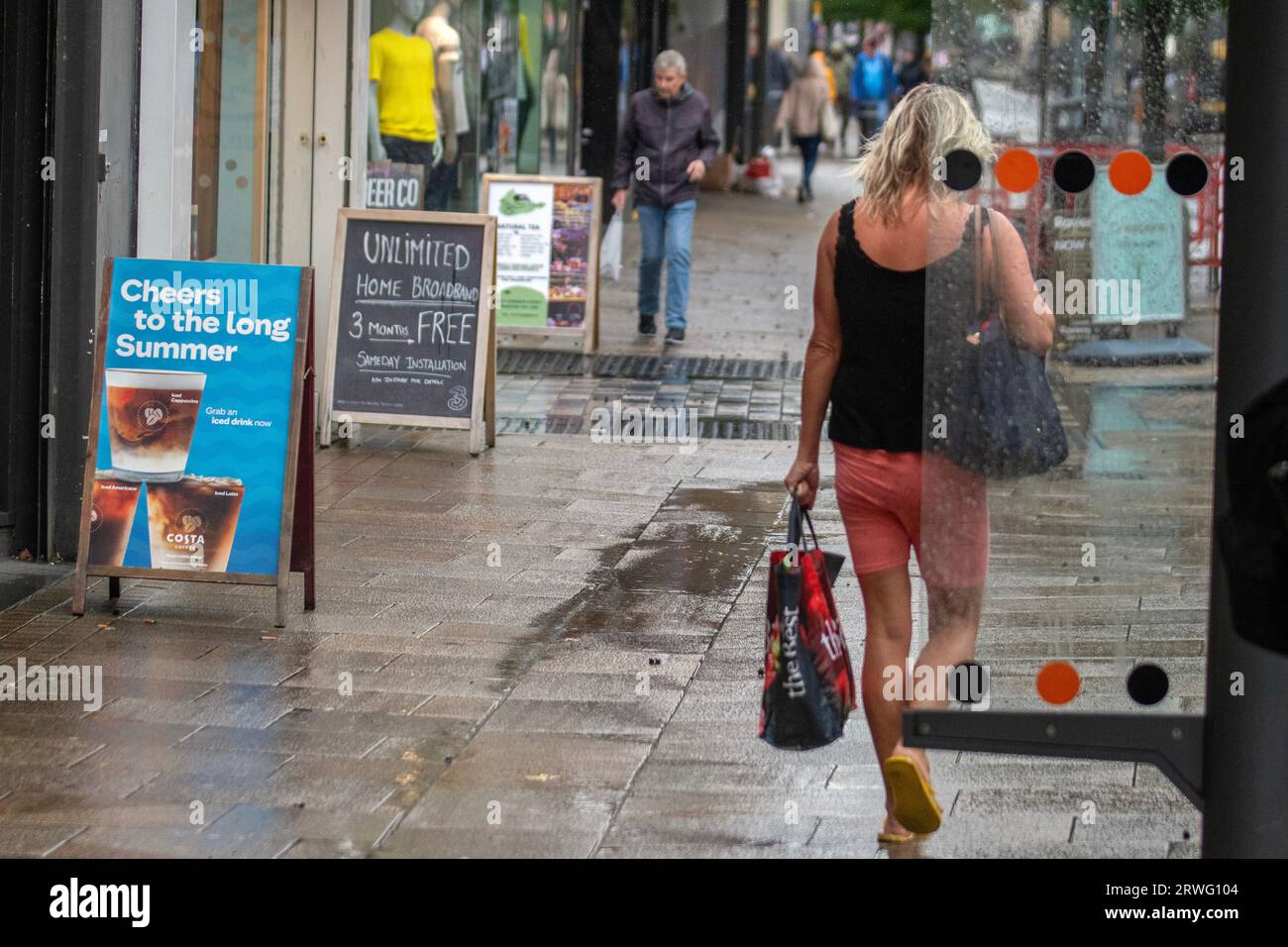 „Cheers to the Long Summer“, Costa Coffee-Schild in Preston, Lancashire. Wetter in Großbritannien September 2023. Shops, Shopper shoppen an einem böigen, windigen Tag mit schweren Duschen in Preston. Es ist windig, mit Stürmen im Westen. Es wird heute Nachmittag mit heftigen und anhaltenden Regenfällen gerechnet. Gutschrift. MediaWorldImages/AlamyLiveNews Stockfoto