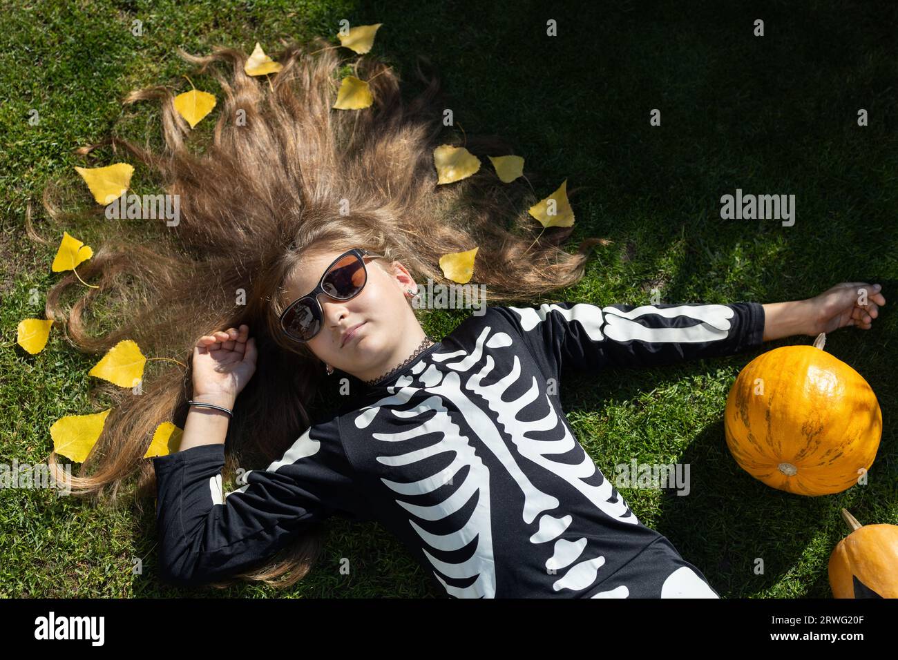 Mädchen im Alter von 10 bis 12 Jahren in einem schwarzen Skelett-Kostüm feiert Halloween im Freien, Stockfoto