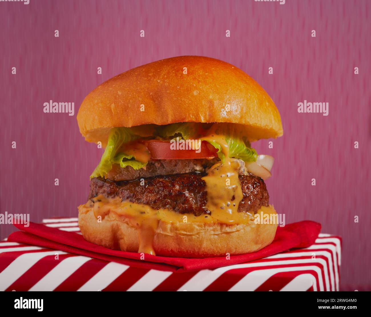 Saftiger, gestapelter Käseburger mit Burger-Relish, der an der Seite runterläuft. Stockfoto