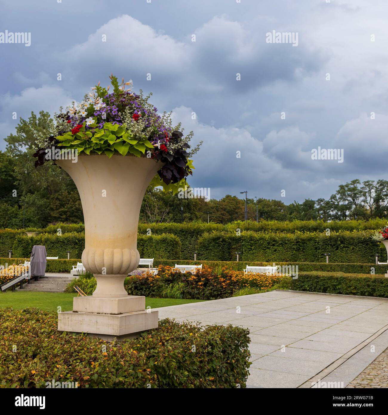 Warschau, Polen - 28. August 2023, die Gärten der königlichen Burg. Hohe Steinvase mit verschiedenen Blumen. Stockfoto