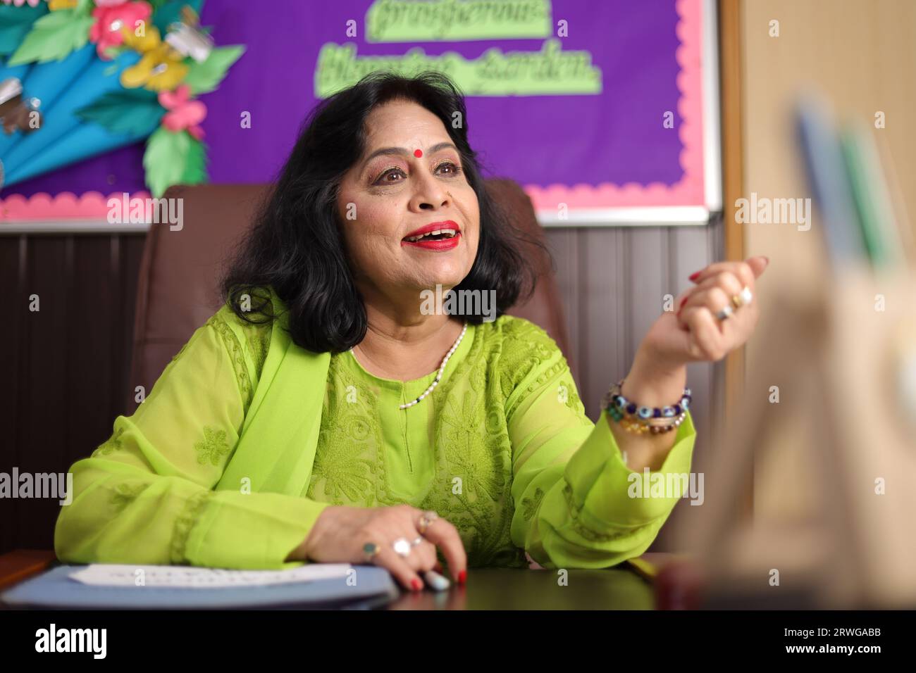 Schulleiterin, glücklich sitzend, stolz auf die Schüler ihrer Schule, lächelnd. Stockfoto