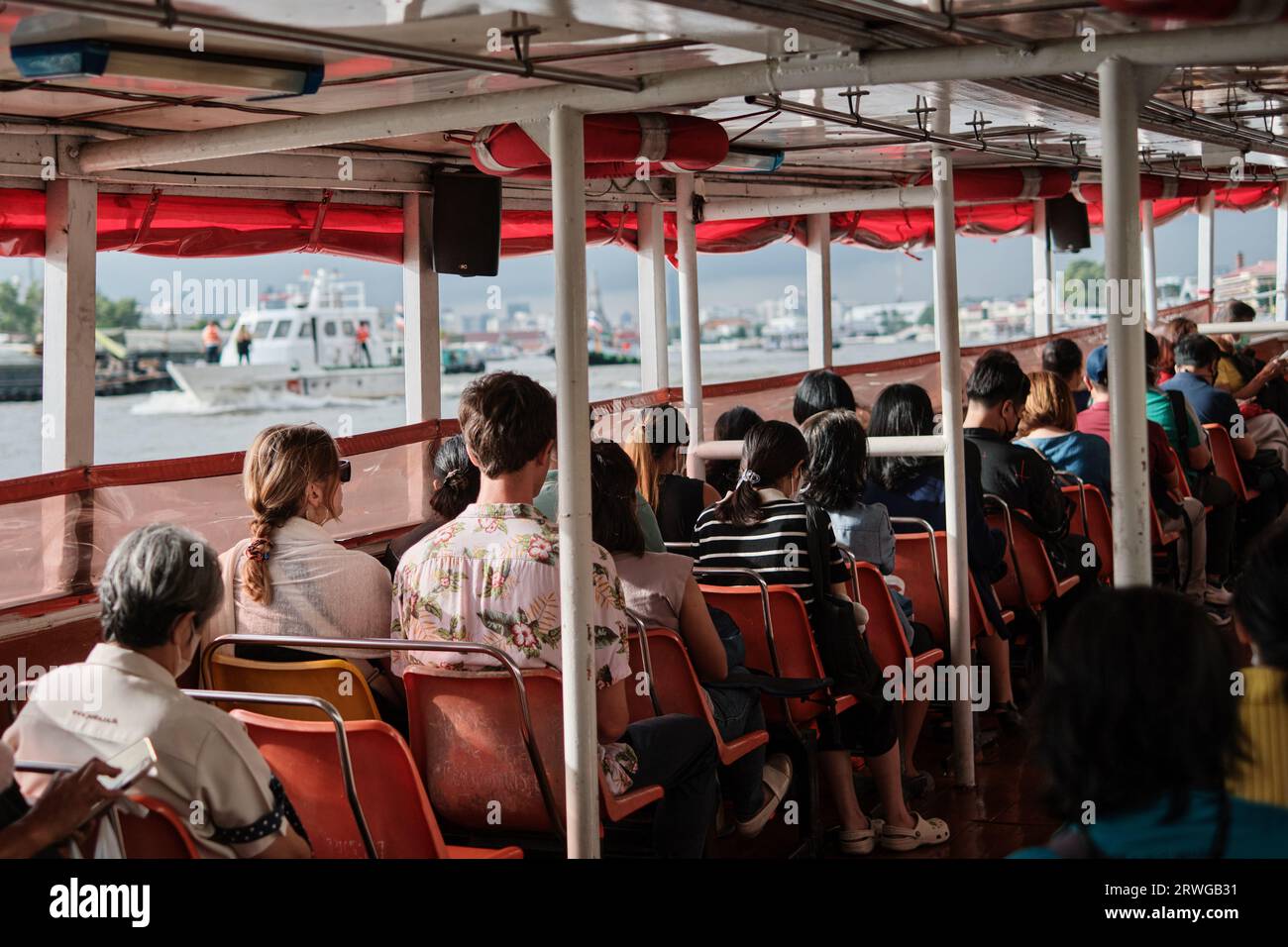 Zwei westliche Touristen und andere Passagiere auf einem Expressboot auf dem Chao Phraya River in Bangkok, Thailand. Vermeiden Sie die verstopften Straßen der Stadt Stockfoto