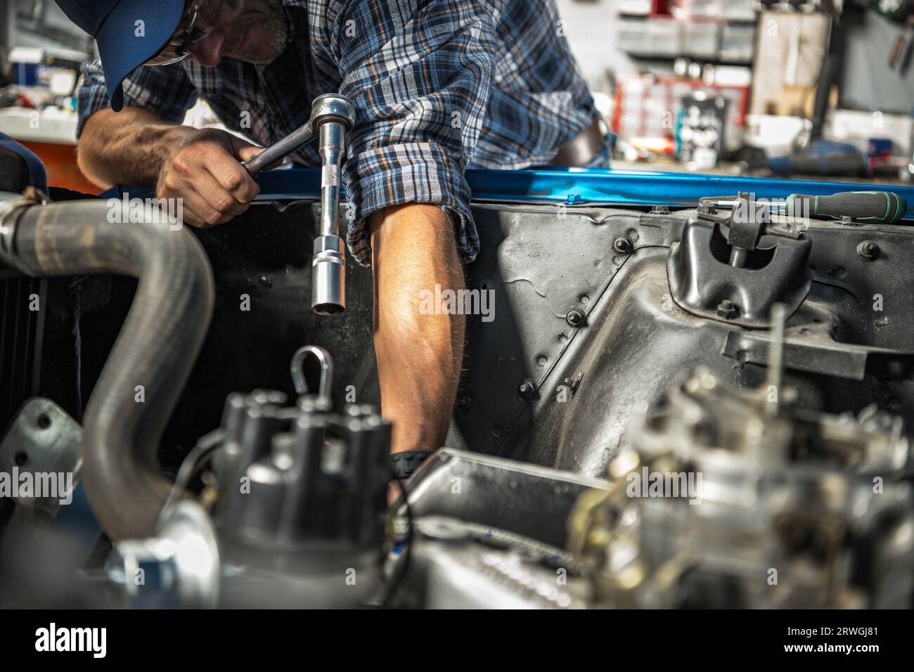 Kaukasischer Berufsmechaniker repariert Benzinmotor in seinem Kundenauto Stockfoto