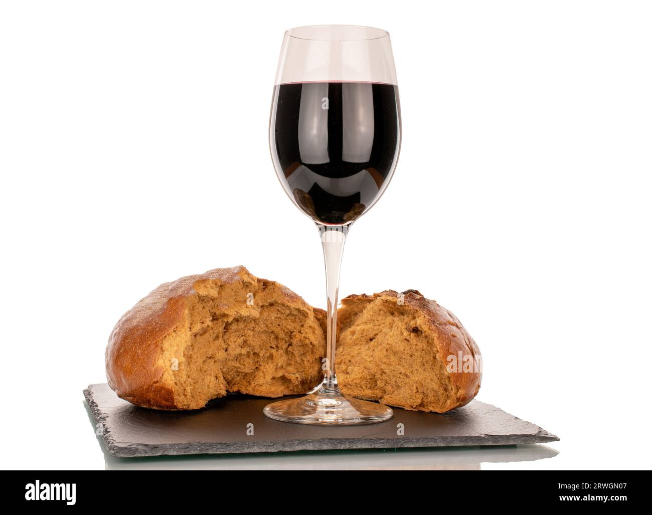 Ein Glas Rotwein und zwei Hälften Brot auf einem Schiefertablett, Makro, isoliert auf weißem Hintergrund. Stockfoto