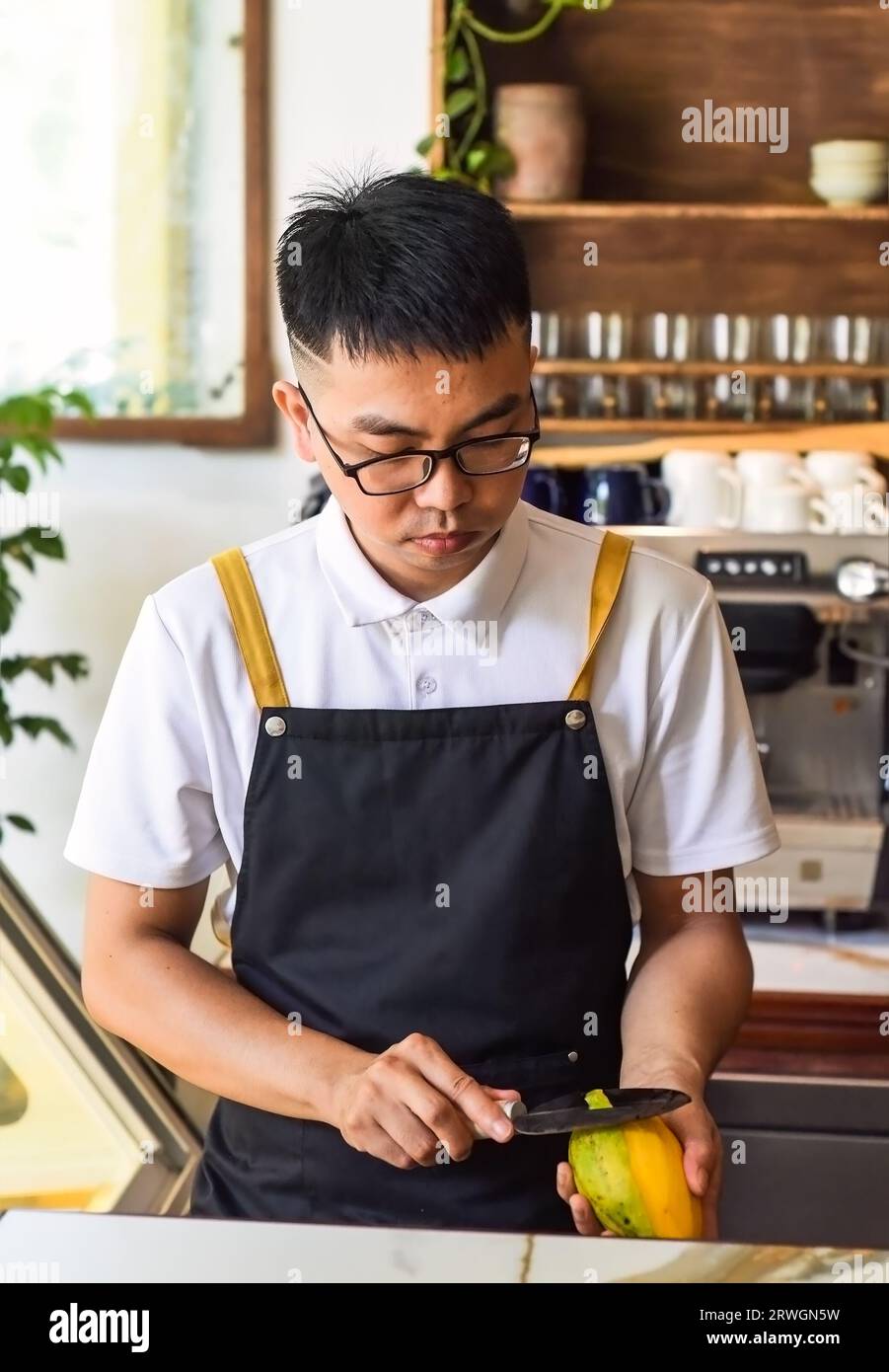 Vietnamesischer Chefkoch, der frische Mango im Café schält Stockfoto