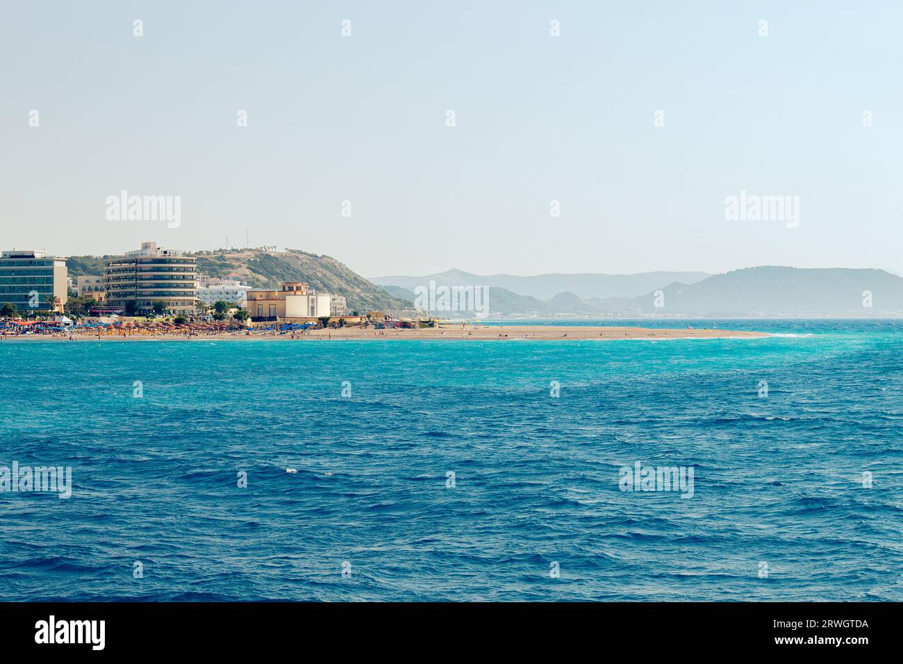 Beliebter Elli Strand oder Paralia Enidriou auf der Insel Rhodos in Griechenland, Europa. Beliebter Sandstrand in der Stadt an sonnigen Sommertagen, blauer Himmel. Vom Meer aus gesehen. Stockfoto