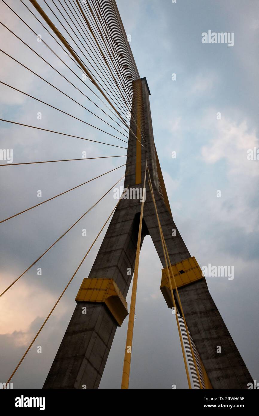 Eine hoch aufragende Hängebrücke mit Betonsäulen und Stahlseilen, bewölkter Himmel. Stockfoto