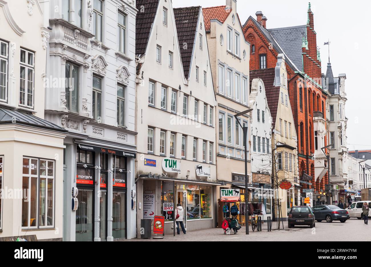 Flensburg, Deutschland - 10. Februar 2017: Straßenansicht der Flensburger Stadt mit traditionellen alten deutschen Häusern tagsüber laufen normale Menschen die Straße entlang Stockfoto