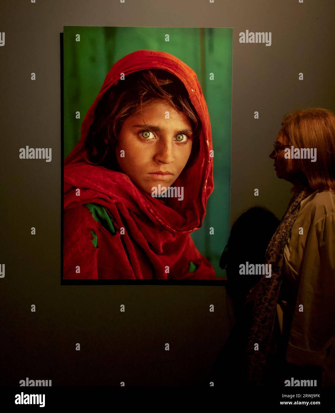 Eine Frau schaut sich Steve McCurrys ikonisches Foto eines afghanischen Mädchens an Stockfoto
