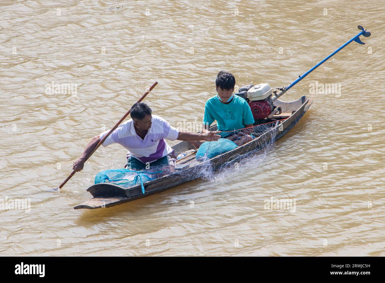 PRACHIN BURI, THAILAND, FEBRUAR 26 2023, Ein Fischer in einem kleinen Boot fängt Fische mit einem Netz Stockfoto