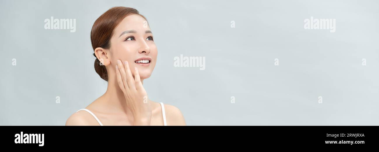 Die asiatische Frau hat ein schönes Gesicht und fühlt sich glücklich mit ihrer perfekten Haut, die ihr Gesicht berührt. Banner Stockfoto