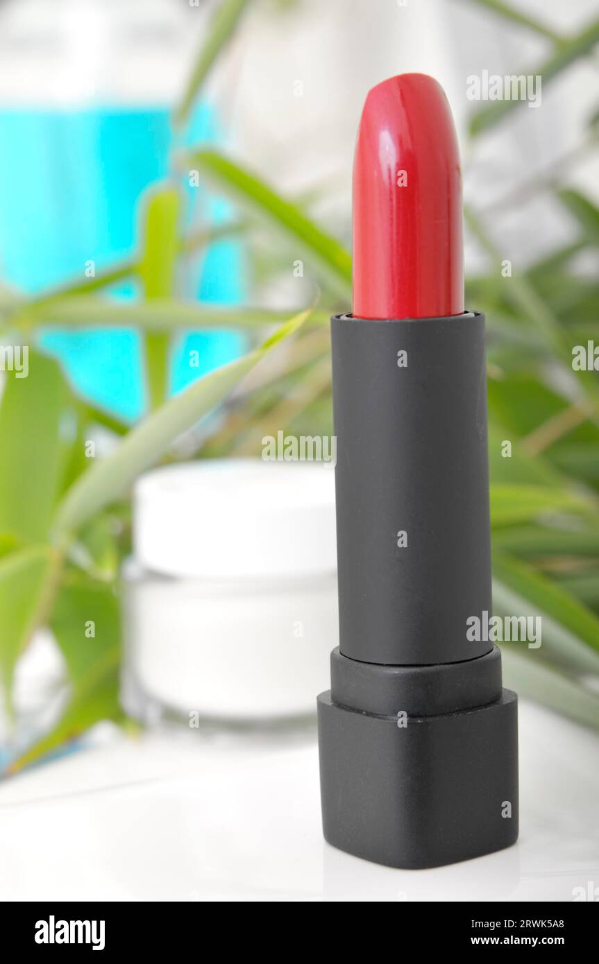 Lippenstift- und Cremebecher mit Bambus- und blauem Seifenspender im Hintergrund Stockfoto