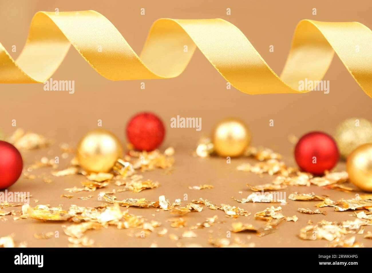 Hintergrund für Produktwerbung. Rote goldene weihnachtskugeln, goldene Papierknallstücke, goldenes Band auf goldenem Hintergrund. Freier Platz Stockfoto