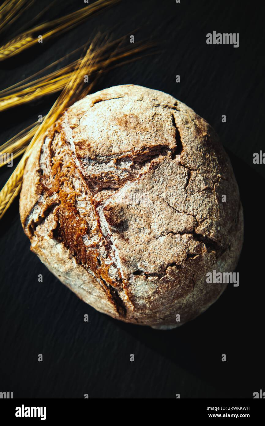 Frisch gebackenes traditionelles Brot auf einem schwarzen Brett. Hefe-freies Roggenbrot, Nahaufnahme. Lebensmittelhintergrund. Stockfoto