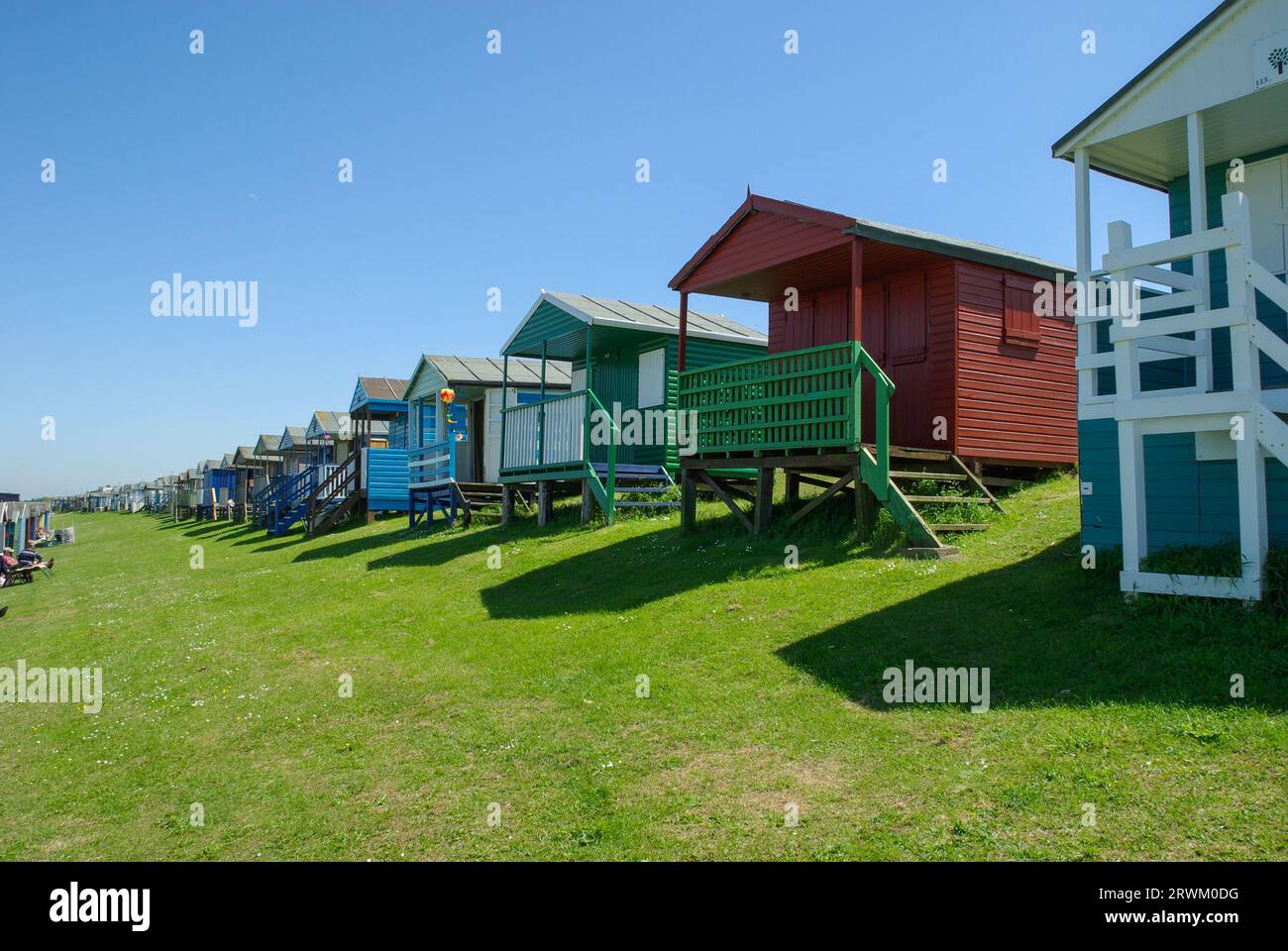 Tankerton Beach kleine Häuser an Tankerton Hängen an der Küste von Whitstable, Kent, Großbritannien. Erhöhte Holzhütten mit Meerblick an einem sonnigen Tag mit blauem Himmel Stockfoto