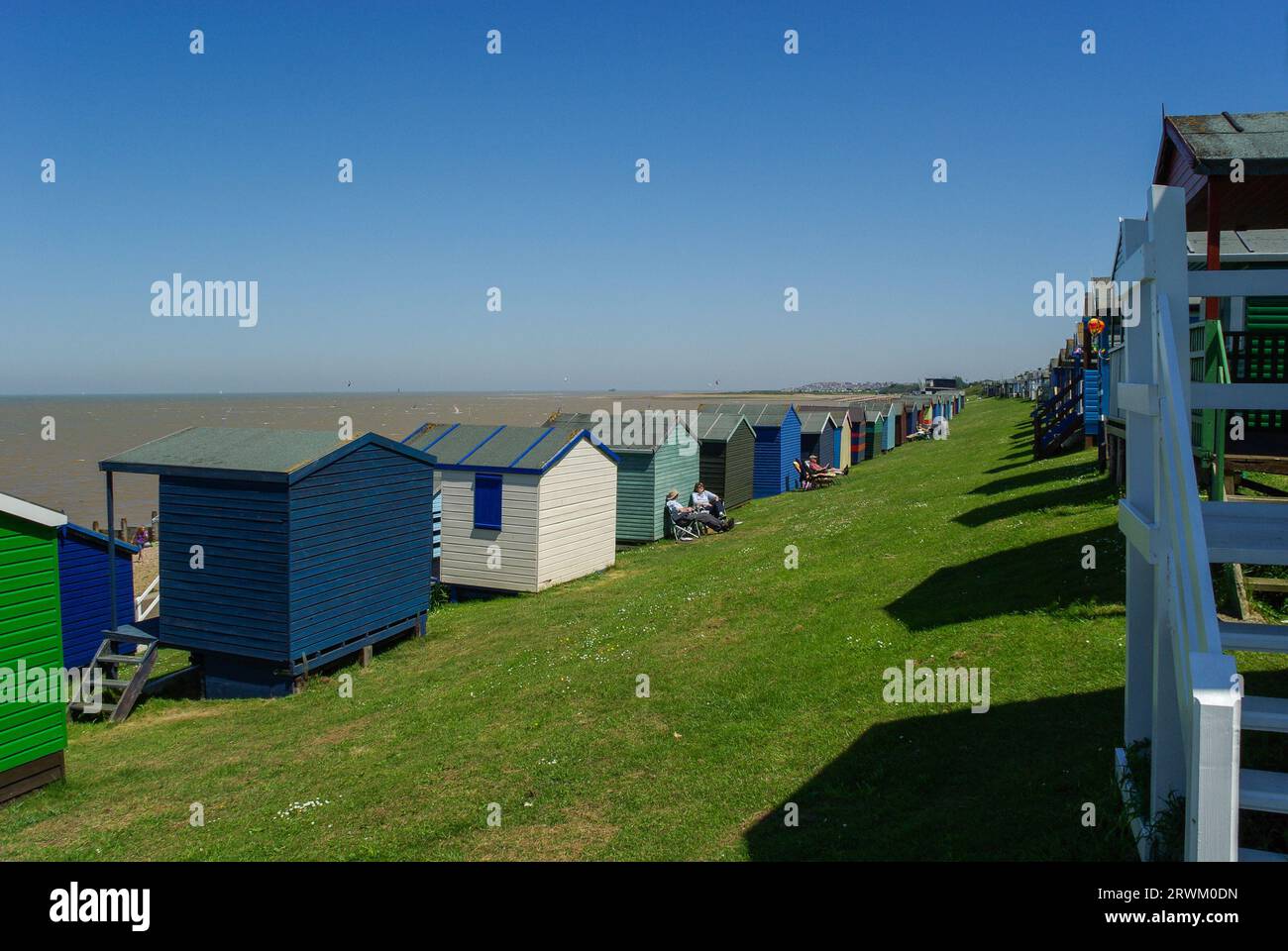 Tankerton Beach kleine Häuser an Tankerton Hängen an der Küste von Whitstable, Kent, Großbritannien. Erhöhte Holzhütten mit Meerblick an einem sonnigen Tag mit blauem Himmel Stockfoto
