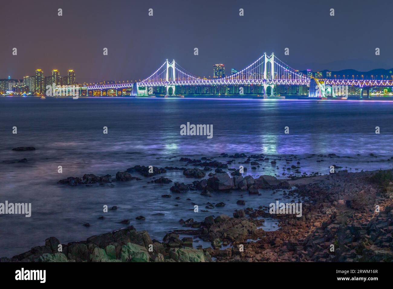 Der nächtliche Blick auf eine Stadt mit einem Strand und einer Brücke Stockfoto