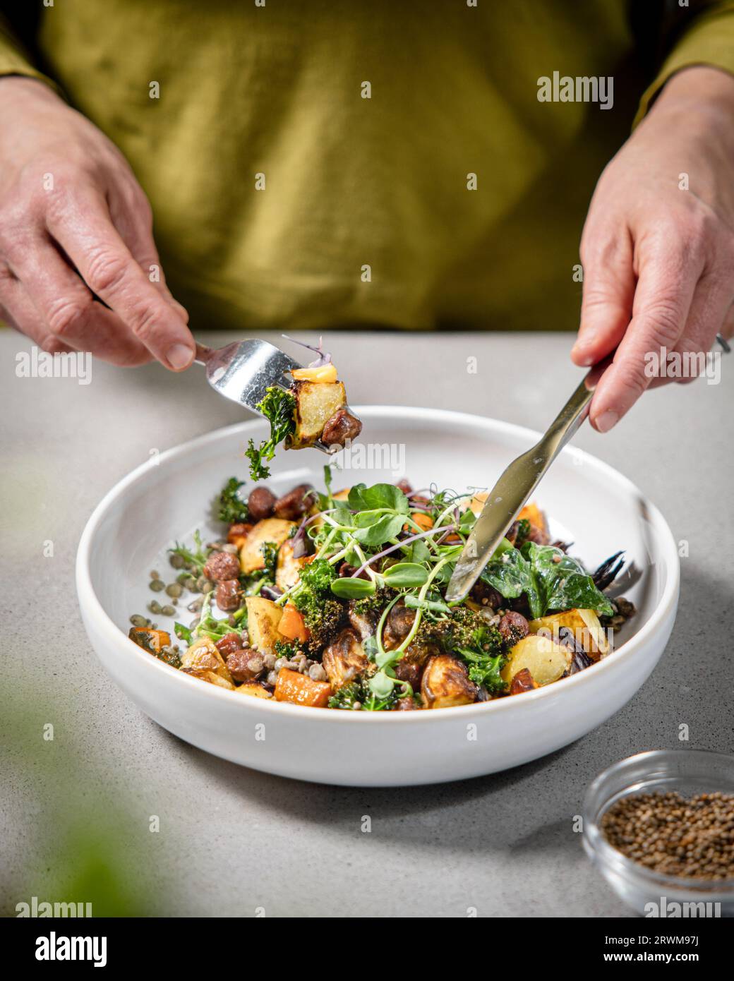 Ein Teller gefüllt mit einem lebendigen und nahrhaften Salat mit einer bunten Mischung aus Kartoffeln, Karotten, Brokkoli, Erbsensprossen und grünen Linsen. Die Platte Stockfoto