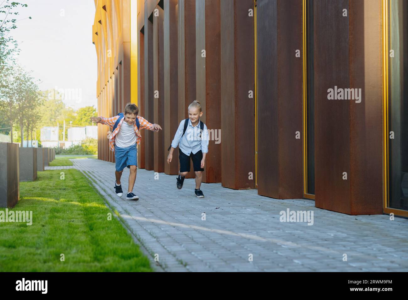 Kaukasische Jungen, die an sonnigen Tagen mit Rucksäcken von der Schule laufen. Beginn des akademischen Jahres. Bild mit selektivem Fokus. Stockfoto