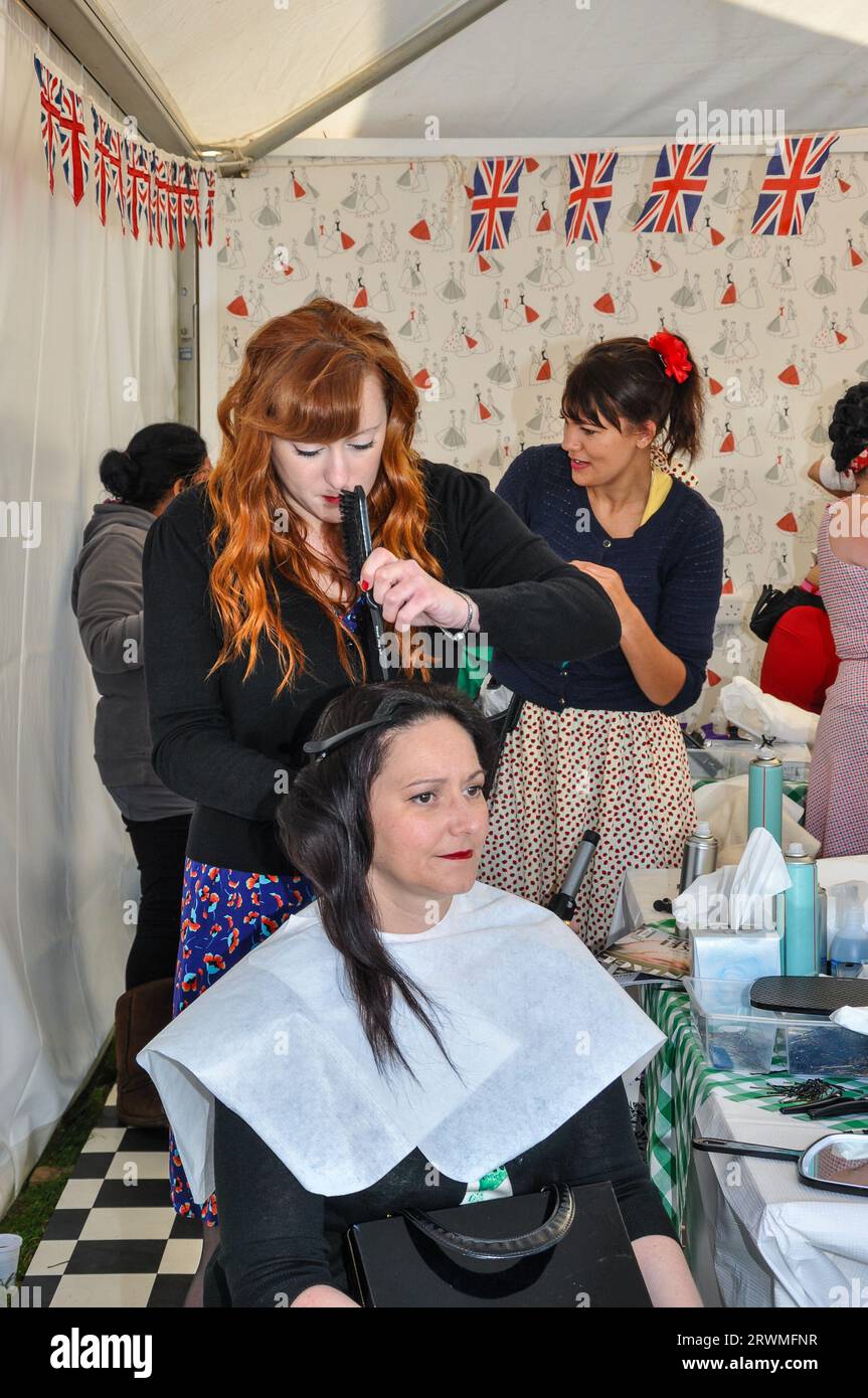 Frauen in einem Friseur- und Schönheitssalon, der im Goodwood Revival, UK, Retro-Mode für die Öffentlichkeit bietet. Haarstylistin bei der Arbeit Stockfoto