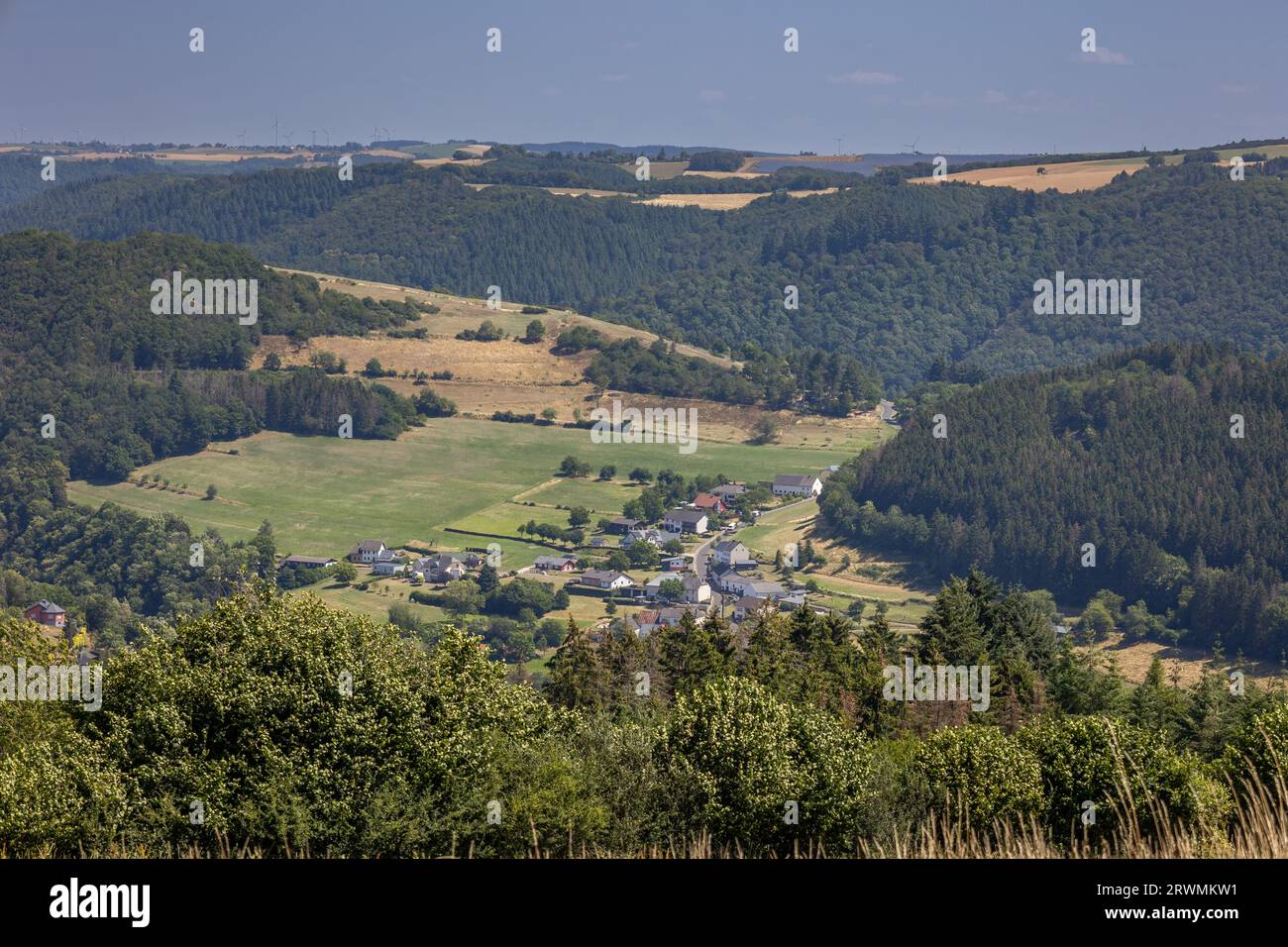 Die Landschaft Luxemburgs mit einem kleinen Dorf im Tal in der Nähe des Mullerthal Naturschutzgebiets mit sanften buschigen Hügeln und einer landwirtschaftlichen Landschaft Stockfoto