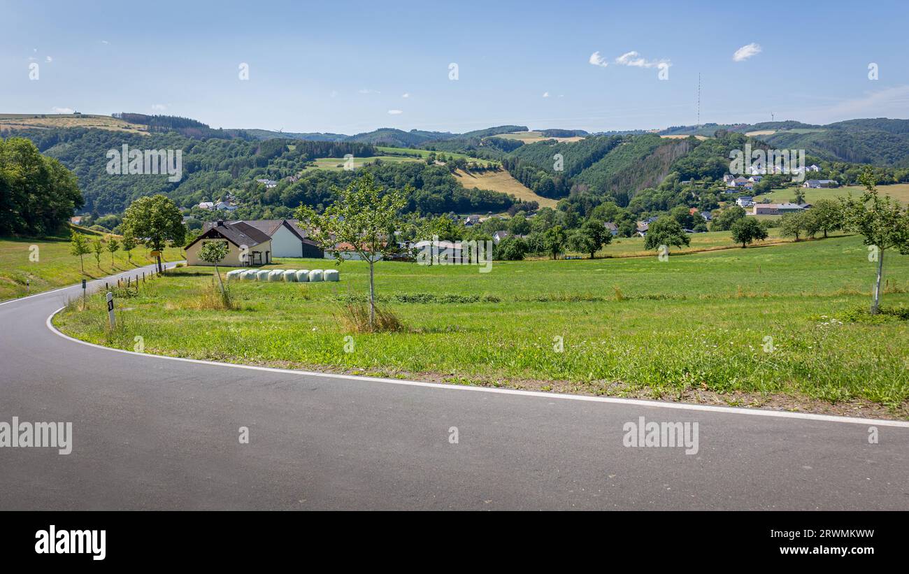 Die Landschaft Luxemburgs mit einem kleinen Dorf im Tal in der Nähe des Mullerthal Naturschutzgebiets mit sanften buschigen Hügeln und einer landwirtschaftlichen Landschaft Stockfoto