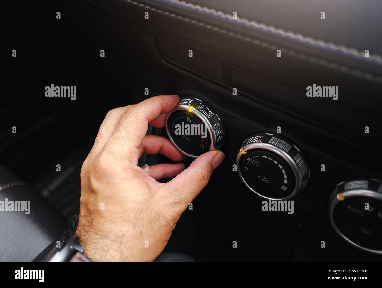 Der Fahrer stellt die Temperatur der Klimaanlage im Fahrzeug ein. Drehen Sie den Schalter, um die Temperatur einzustellen. Stockfoto