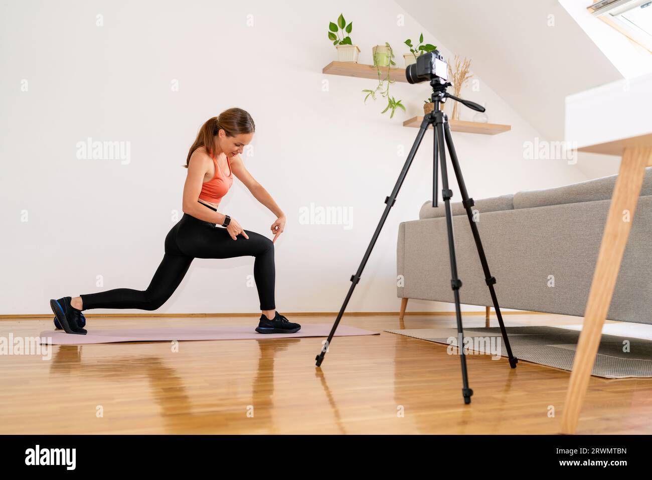 Weibliche Fitnesstrainerin Video-Bloggerin, die Trainingsvideos für ihren Kanal in ihren sozialen Medien aufnimmt. Stockfoto