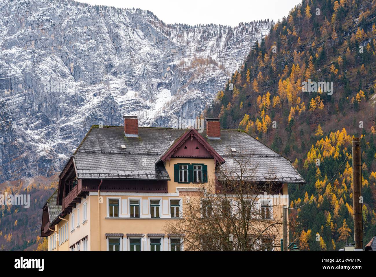 Gebäude mit Alpenbergen im Hintergrund - schneebedeckt und herbstlich bewachsen - Hallstatt, Österreich Stockfoto