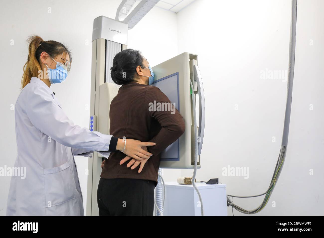 LUANNAN COUNTY, China - 11. Februar 2022: Der Arzt wies den Patienten an, sich vor der Röntgendurchleuchtungsmaschine zu posieren und sich auf die Röntgenaufnahme vorzubereiten Stockfoto