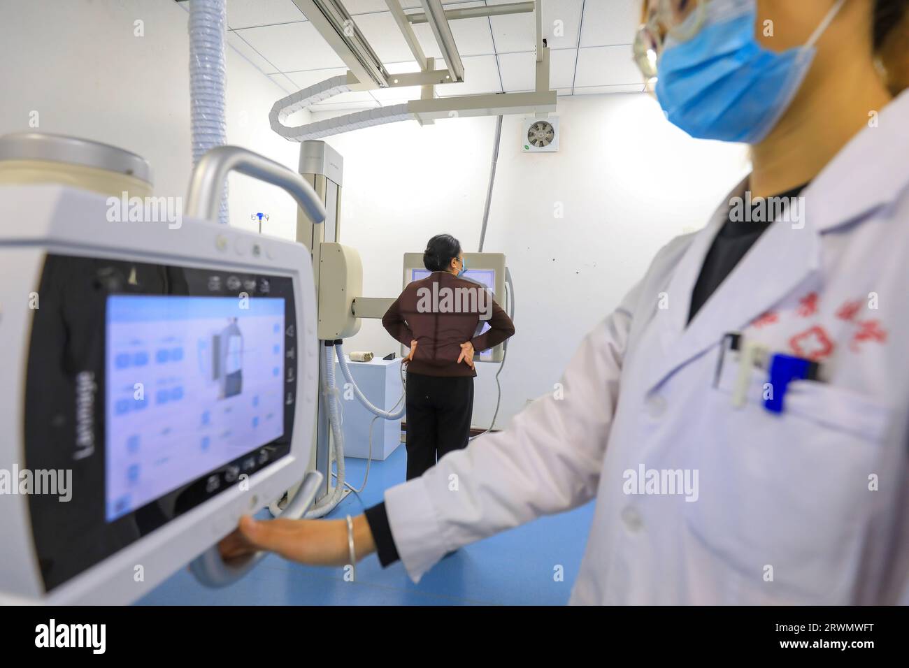 LUANNAN COUNTY, China - 11. Februar 2022: Der Arzt wies den Patienten an, sich vor der Röntgendurchleuchtungsmaschine zu posieren und sich auf die Röntgenaufnahme vorzubereiten Stockfoto