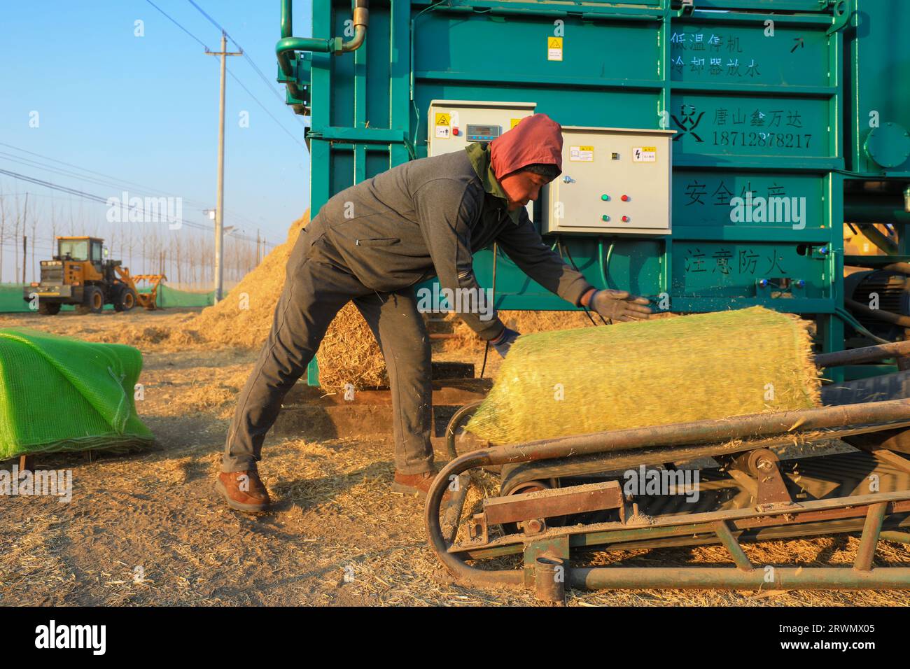 LUANNAN COUNTY, China - 4. Januar 2022: Farmers Operate Machines for Rice Stroh Briquetting, North China Stockfoto