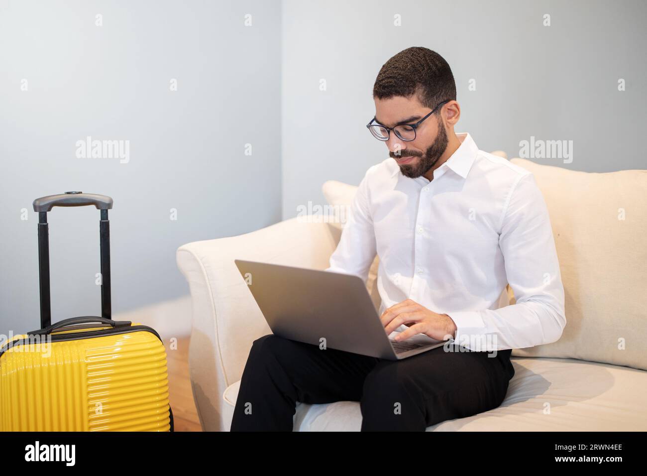 Junger Geschäftsmann aus dem Nahen Osten mit Laptop-Computer in der Hotel Hall Stockfoto