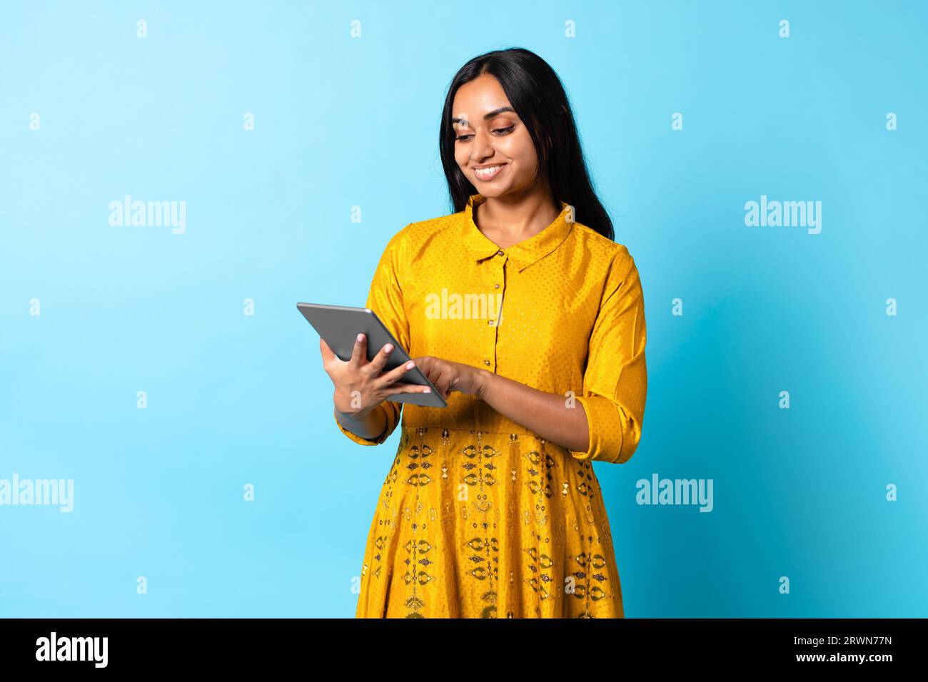 Indische Dame In Traditionellem Kleid Mit Digitalem Tablet, Blauer Hintergrund Stockfoto