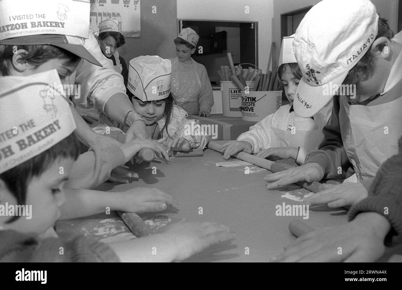 Jüdische Kinder aus den hebräischen Gemeinden Birmingham und Solihull, die im März 1991 an einer Matzo-Bäckerei vor dem PASSOVER im Lubavitch Centre in der Willows Road Birmingham teilnahmen. Den Kindern die Regeln des Backens des ungesäuerten Brotes beibringen Rabbiner Herchel Rader, Minister der Solihull-Synagoge und Professor Sam Aburdaram, Leiter der Solihull-Cheder-Schule Stockfoto