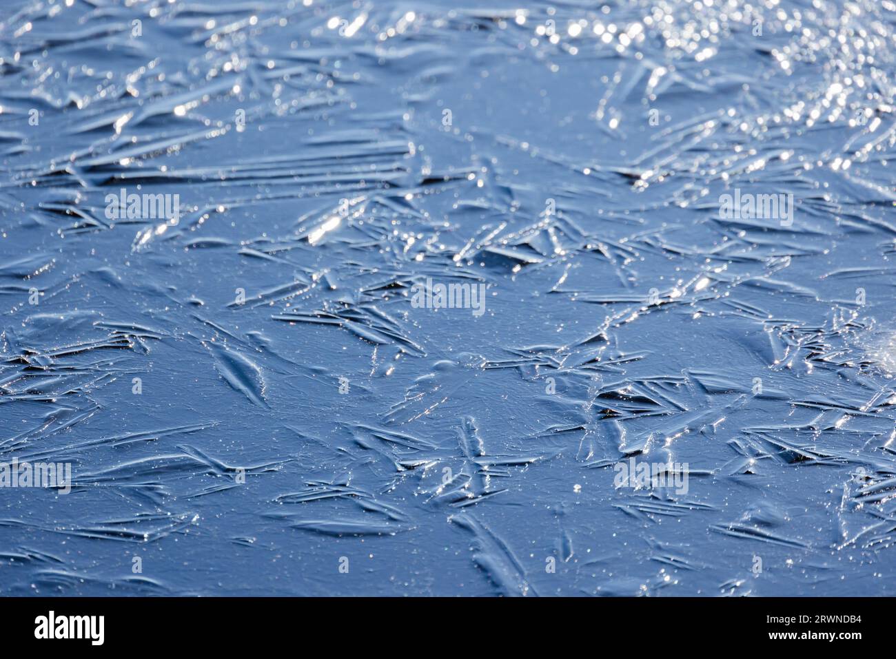 Dünne Eisoberfläche auf einem gefrorenen See, natürliches Hintergrundfoto mit selektivem Weichzeichner Stockfoto