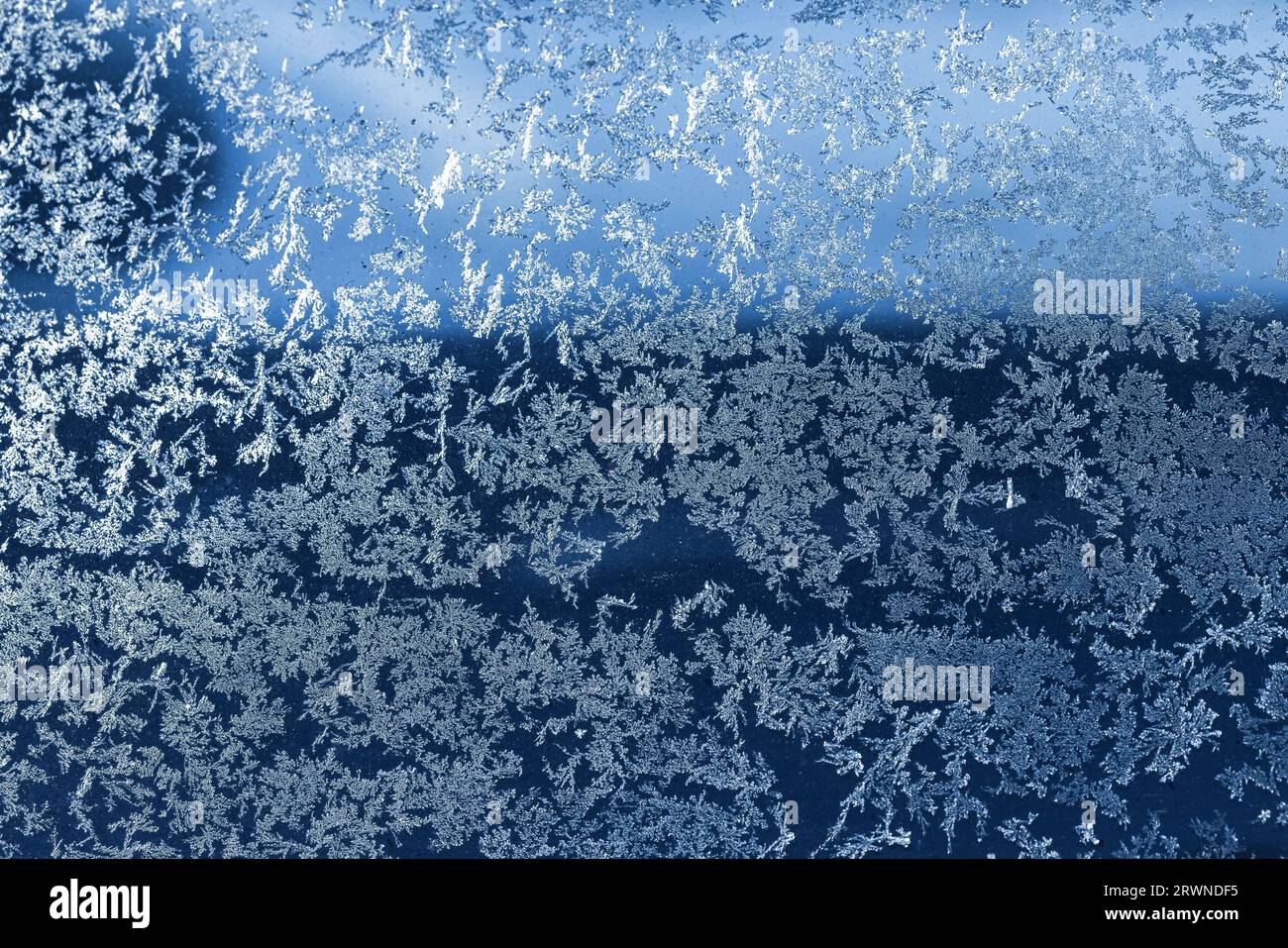 Frostmuster, das das Fensterglas bedeckt, abstrakte Hintergrundfotostruktur Stockfoto