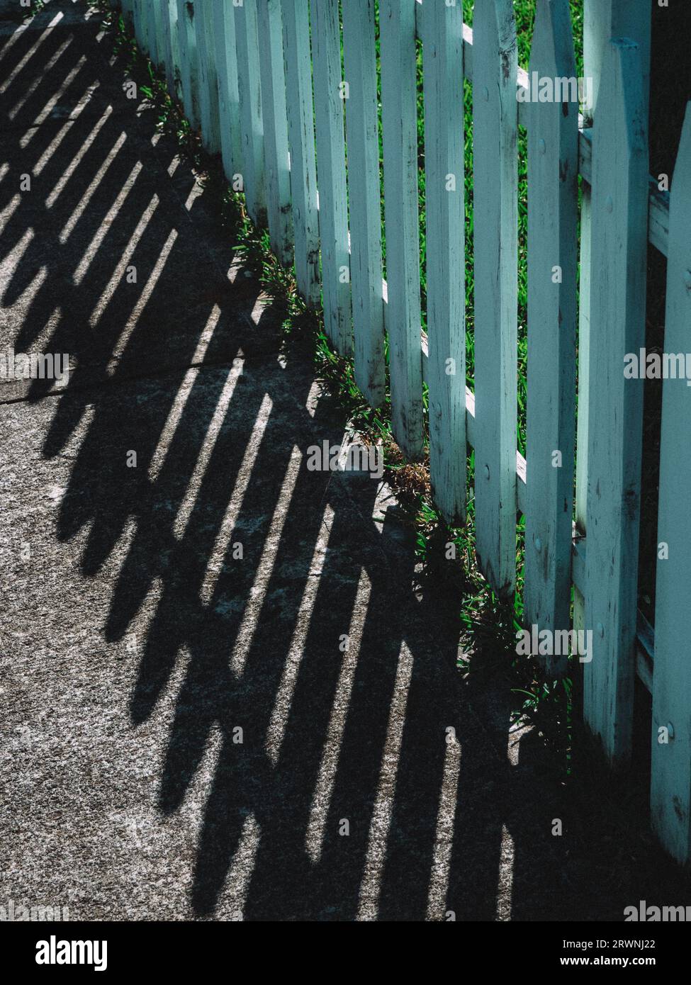 Altmodischer hellblauer Zaun, der Schatten wirft, früh an einem sonnigen Sommermorgen Stockfoto